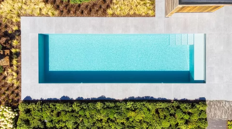 Zwembad zicht van bovenaf omgeven door grote grijze stenen tegels